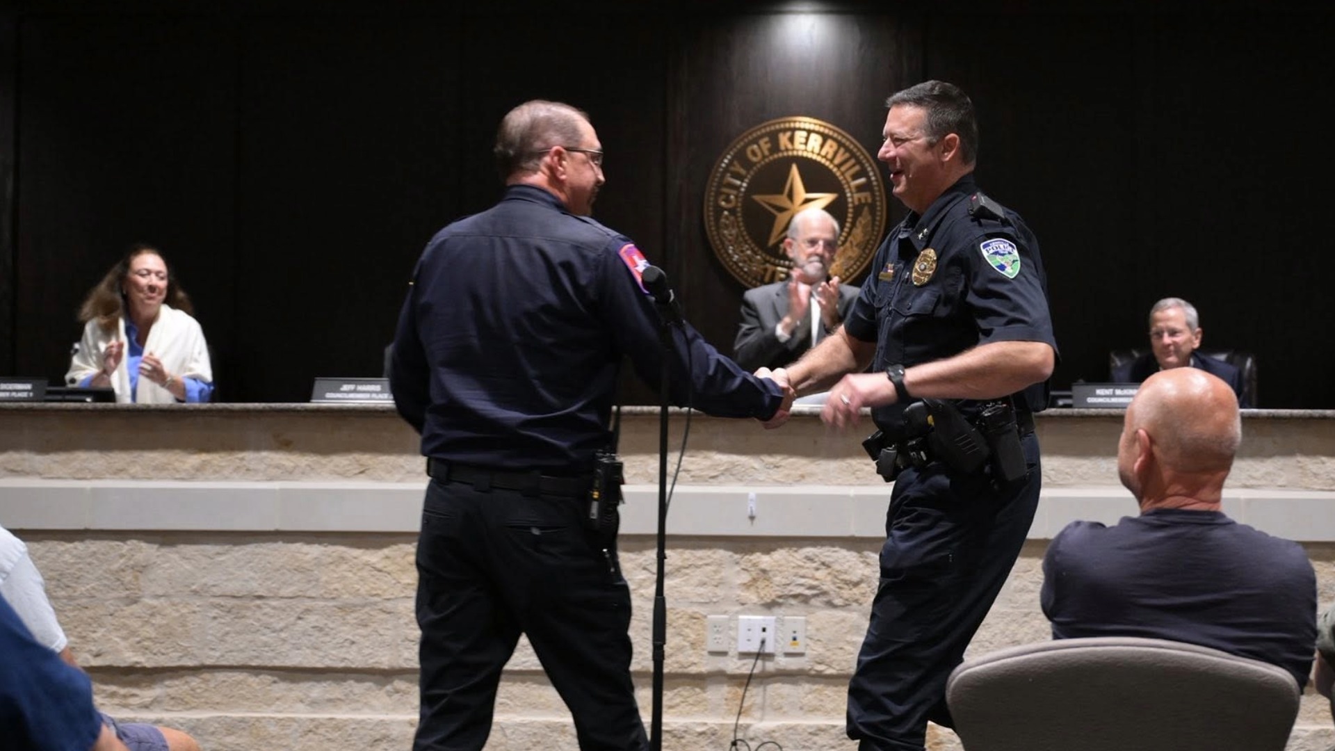 Police Chief Chris McCall applauded beneath the City of Kerrville seal at City Council.